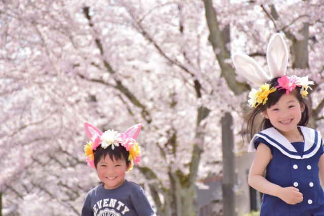 桜の木下でカチューシャをつけて楽しそうに走る子供たち